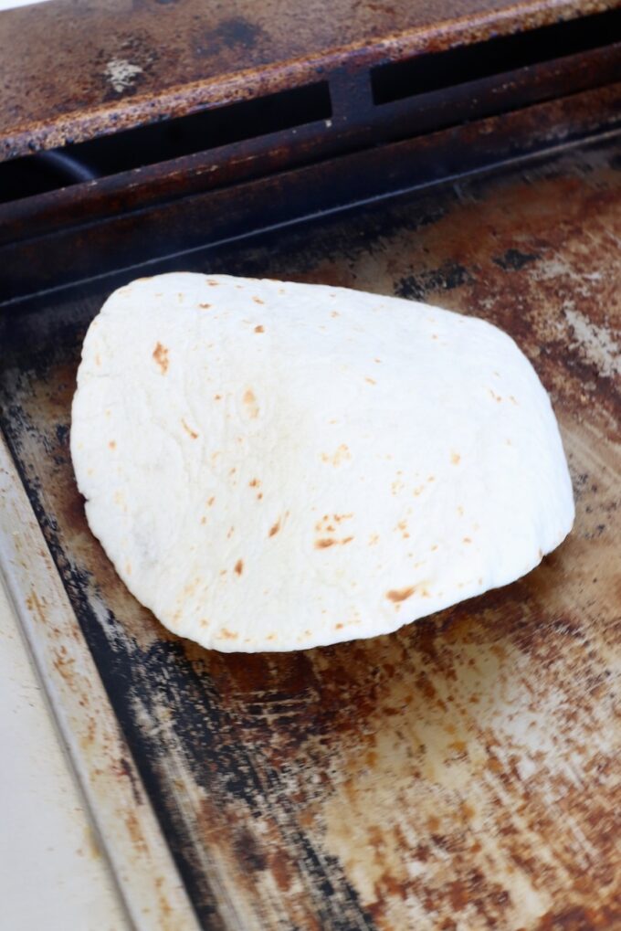 tortilla on top of a ball of beef on a griddle