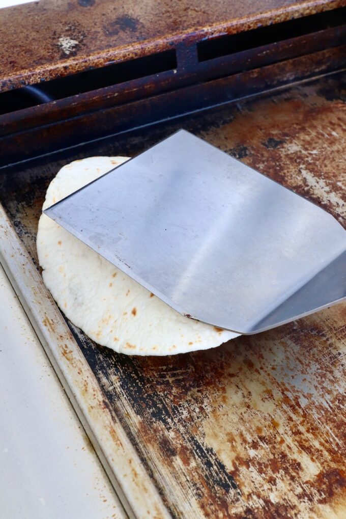 spatula smashing a tortilla on a griddle