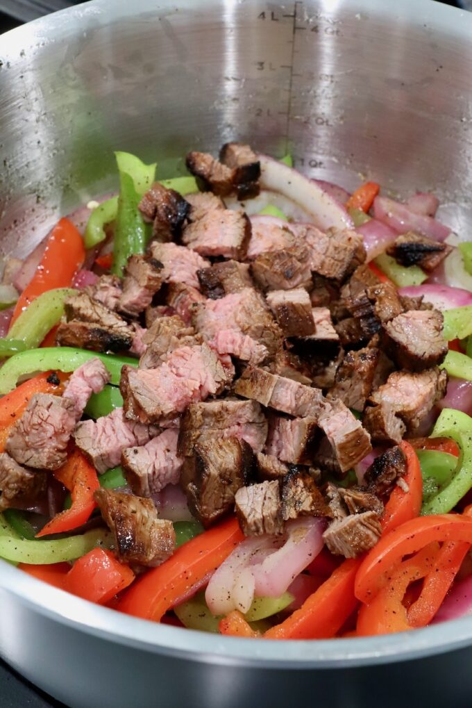 fajita veggies in pot on stove with diced grilled steak