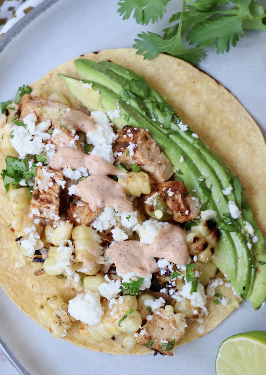 taco on plate topped with avocado and chili lime sauce