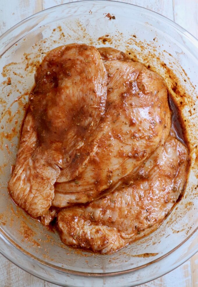 chicken breasts in marinade in glass bowl