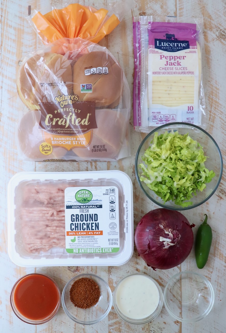 ingredients for buffalo chicken smash burgers on a white wood board