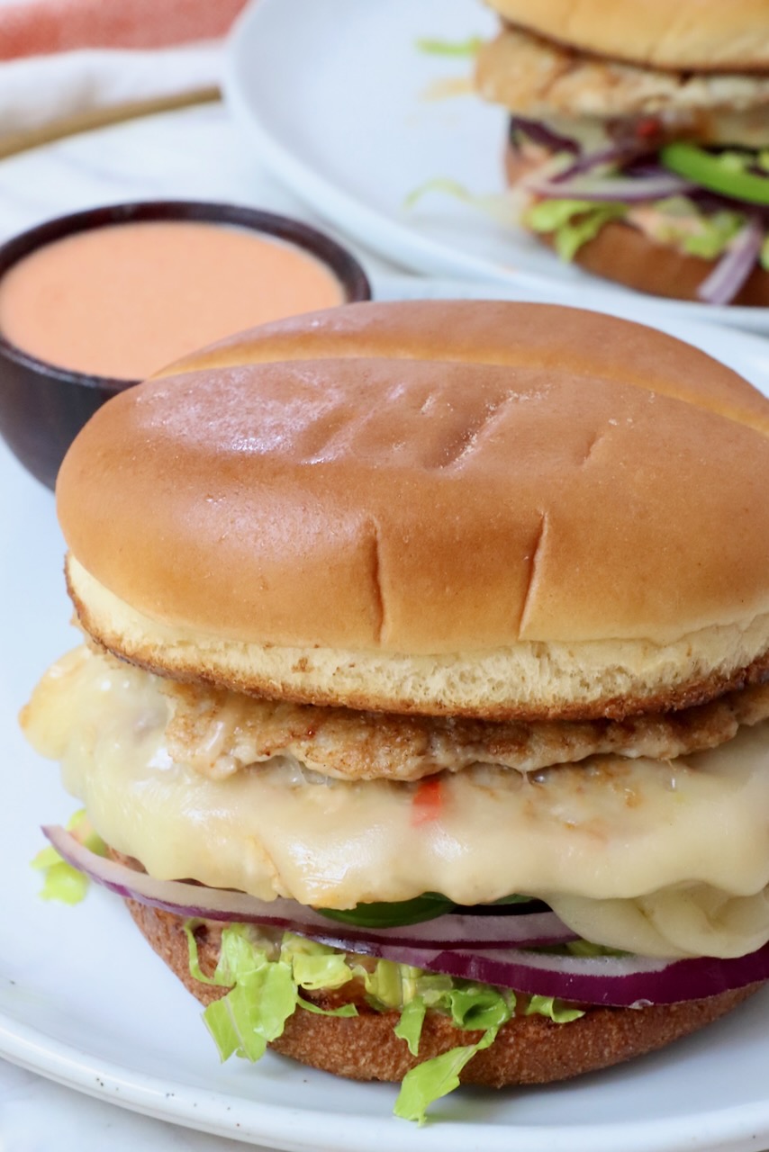 buffalo chicken smash burger on plate with small bowl of buffalo sauce on the side