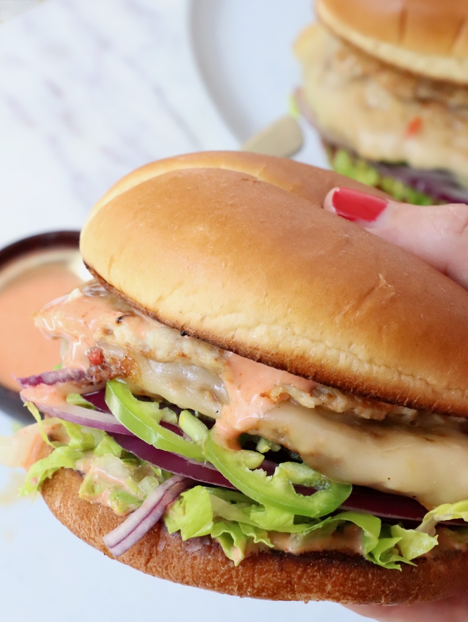 hand holding chicken smash burger over a plate