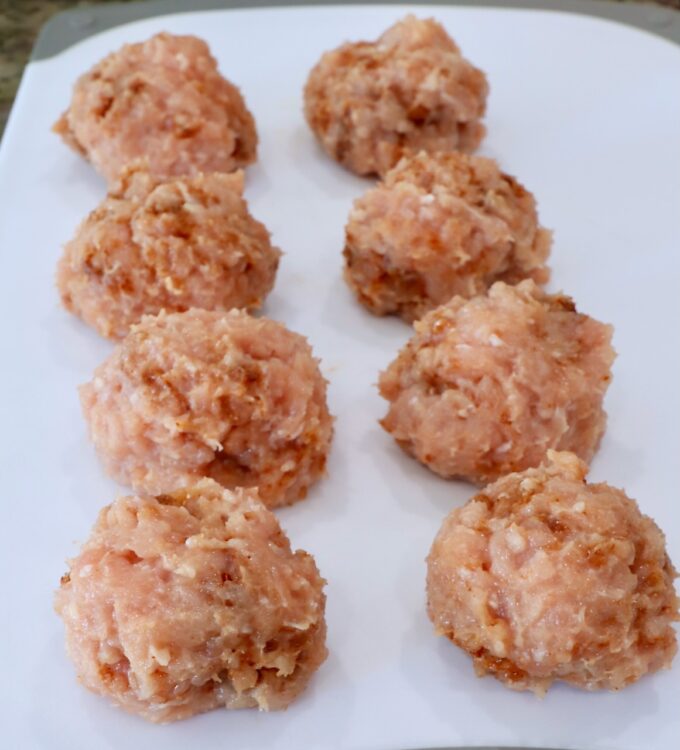 seasoned balls of ground chicken on a white cutting board