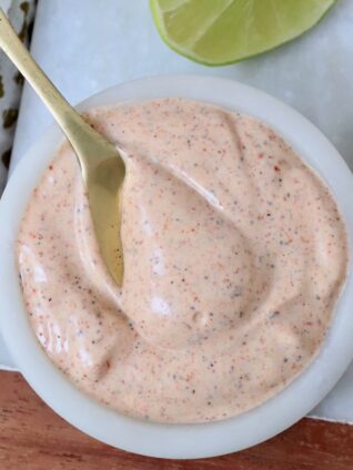 chili lime dressing in a white bowl with a gold spoon