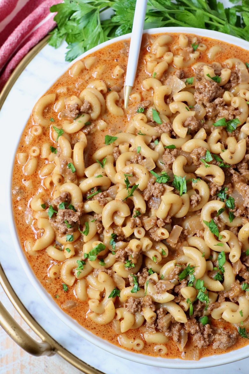 cooked ground beef and pasta combined with sauce in a bowl with a spoon