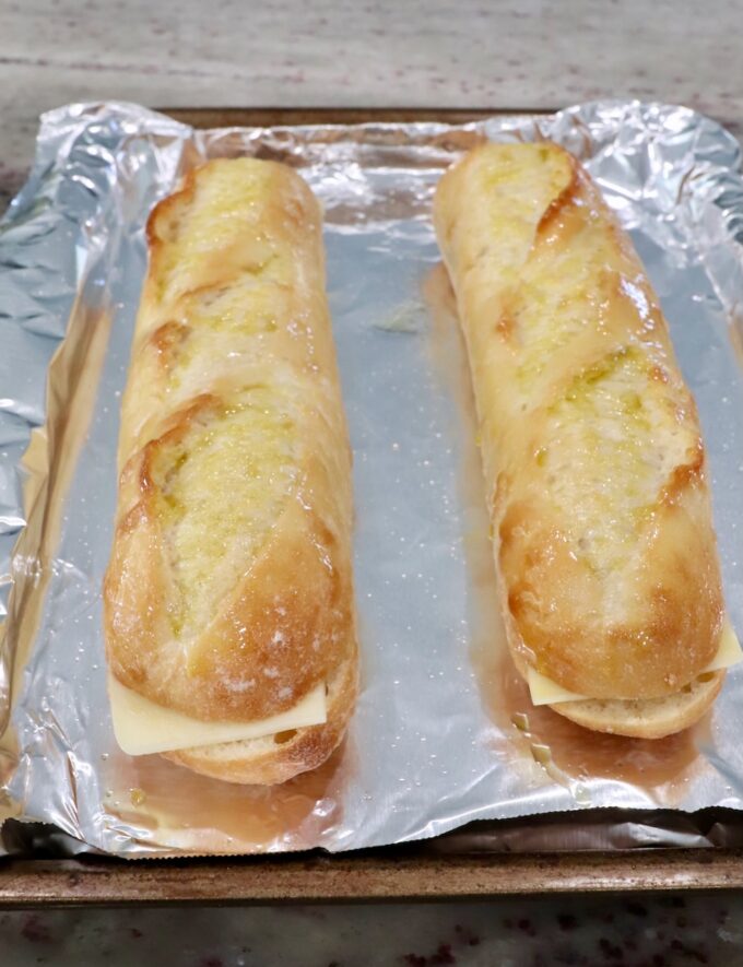 baguettes filled with mozzarella cheese on foil lined baking sheet