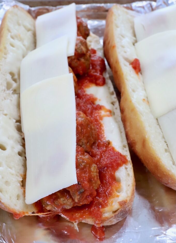 meatballs tossed in marinara sauce in a baguette topped with slices of mozzarella cheese