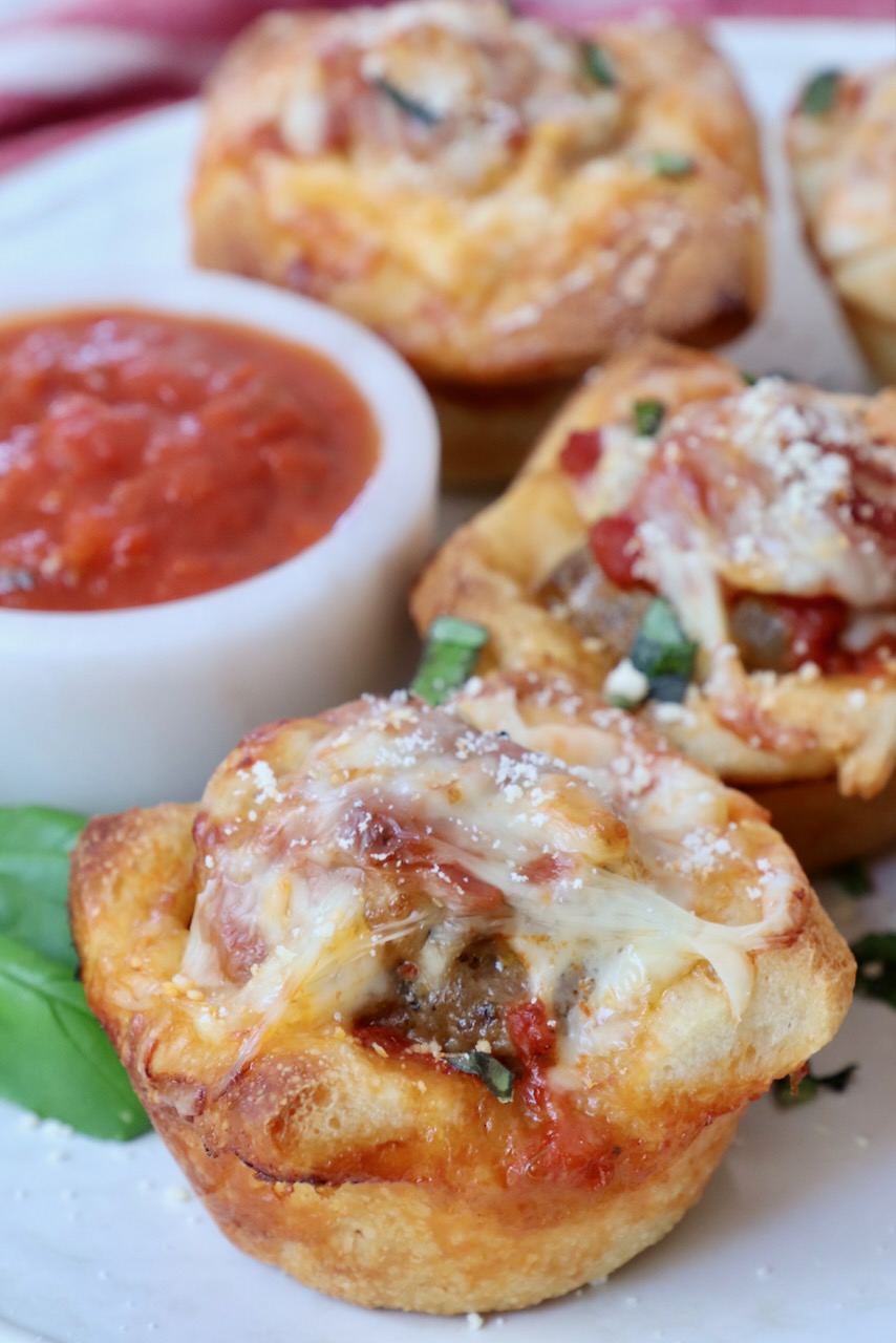 cooked meatball sub bites on a plate with a small bowl of marinara sauce