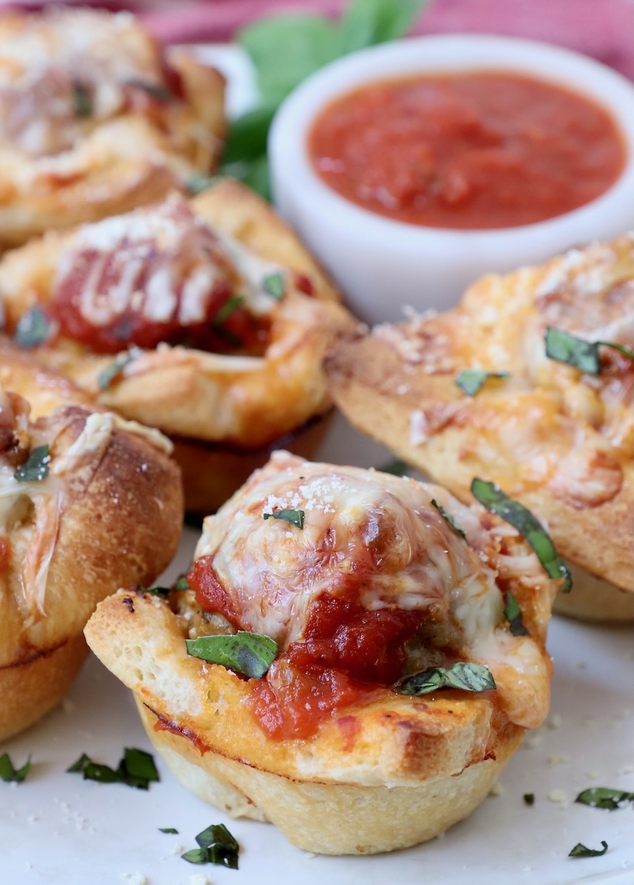 meatball sub bites on a plate with a small bowl of marinara sauce