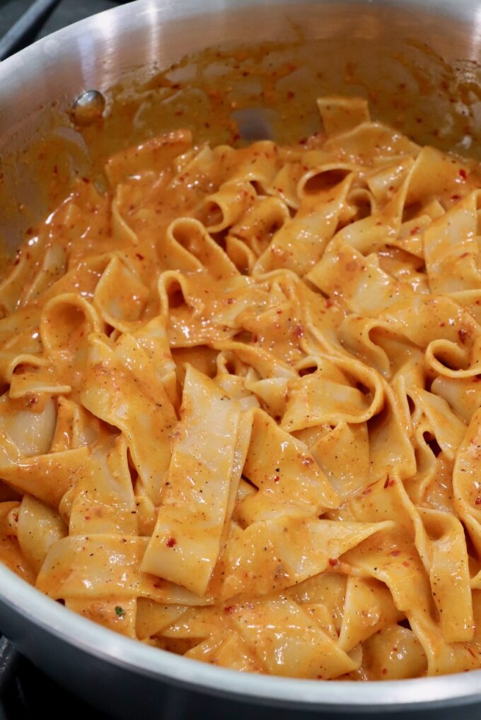 pappardelle pasta noodles tossed with nduja sauce in a pan