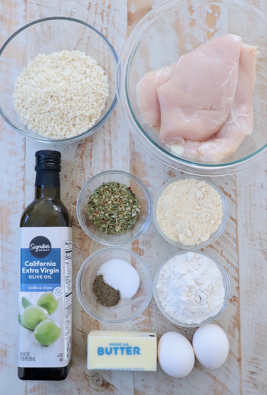 ingredients for parmesan crusted chicken on white wood board