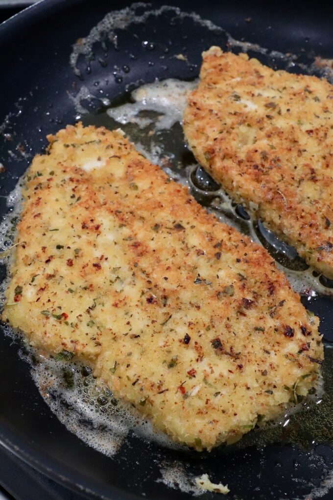 cooked parmesan crusted chicken breasts in a skillet on the stove