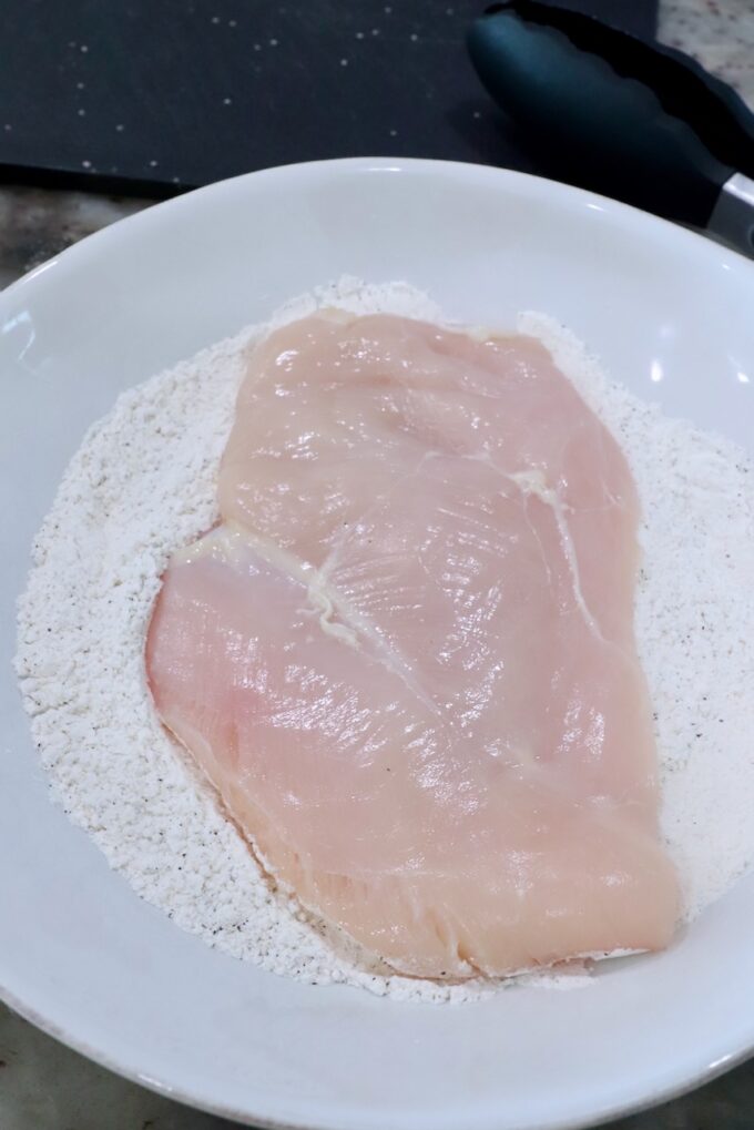 chicken breast in a bowl of flour