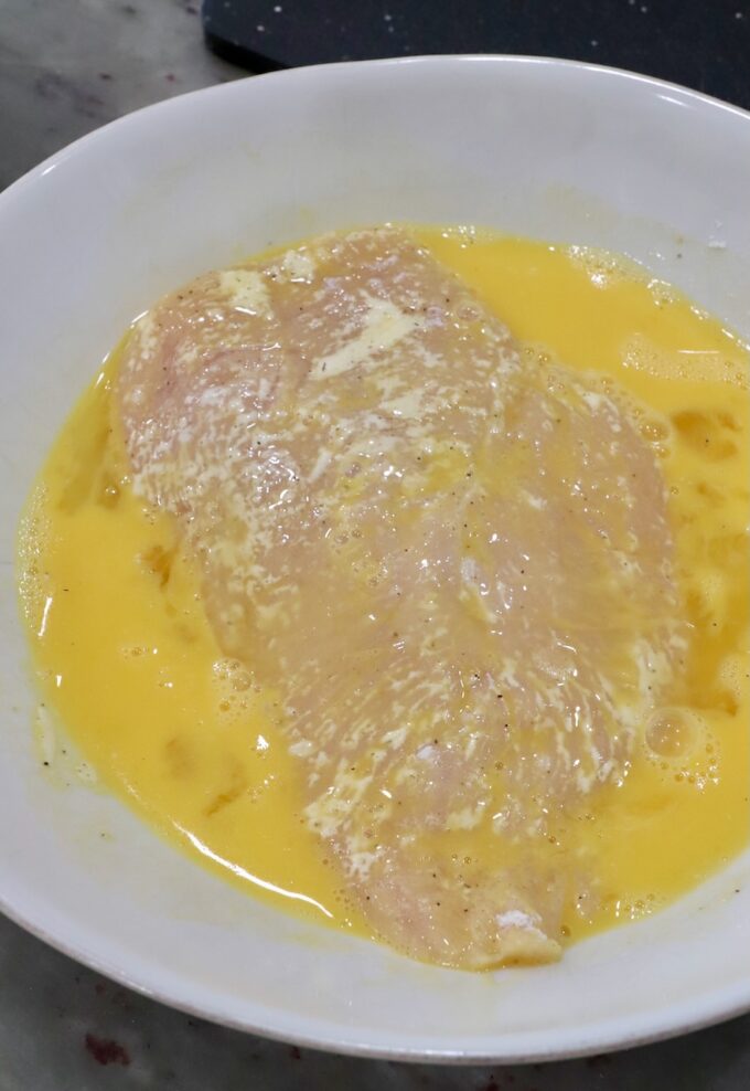 chicken breast in a bowl of whisked eggs