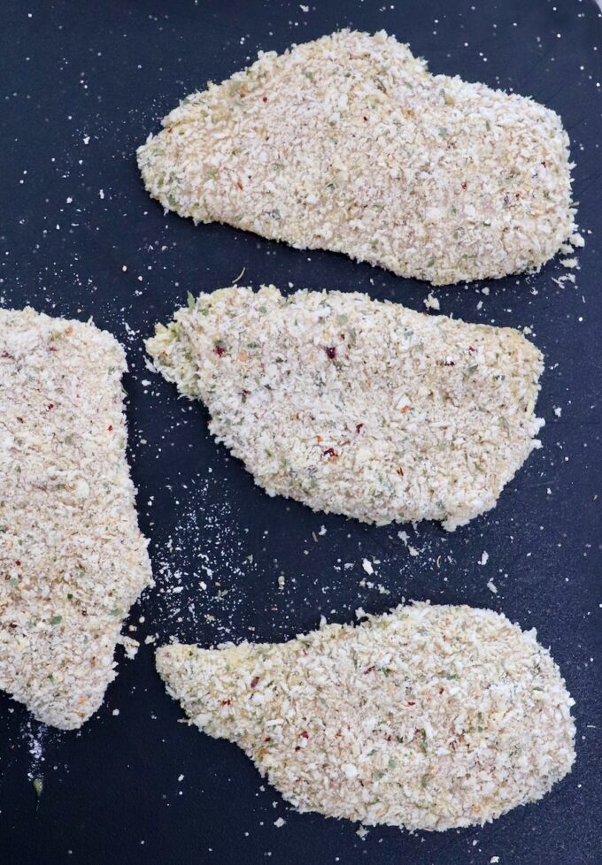 breadcrumb coated chicken breasts on a cutting board