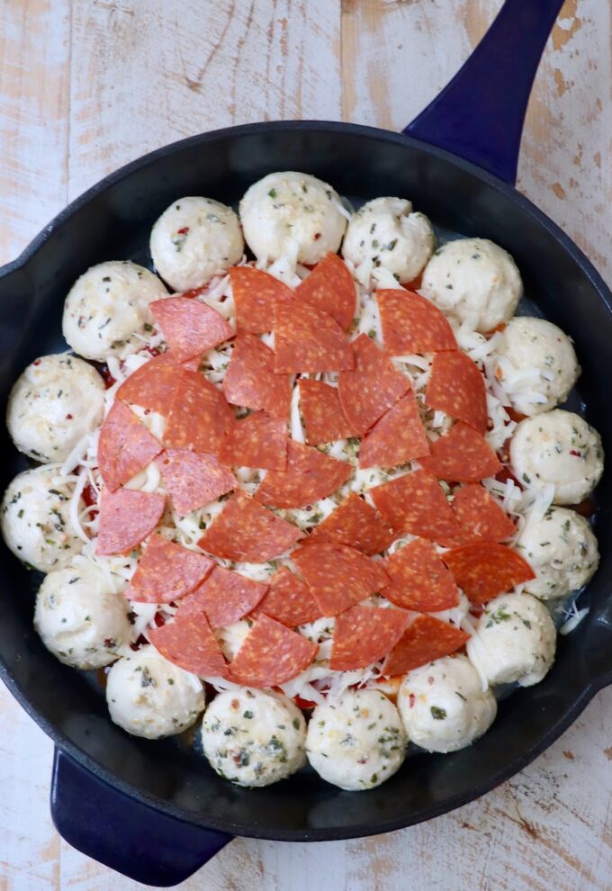 pepperoni pizza dip in the middle of a skillet surrounded by balls of dough