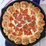 pizza dip in a skillet with pull apart bread surrounding the dip