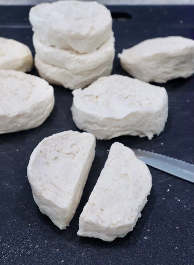 refrigerated biscuit dough cut in half on a cutting board