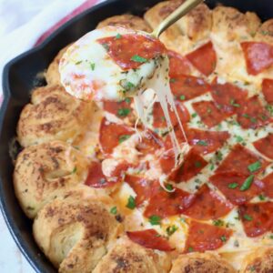 pizza dip in skillet with spoon dipped into it