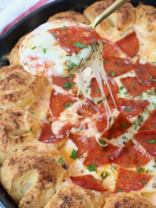 pizza dip in skillet with spoon dipped into it