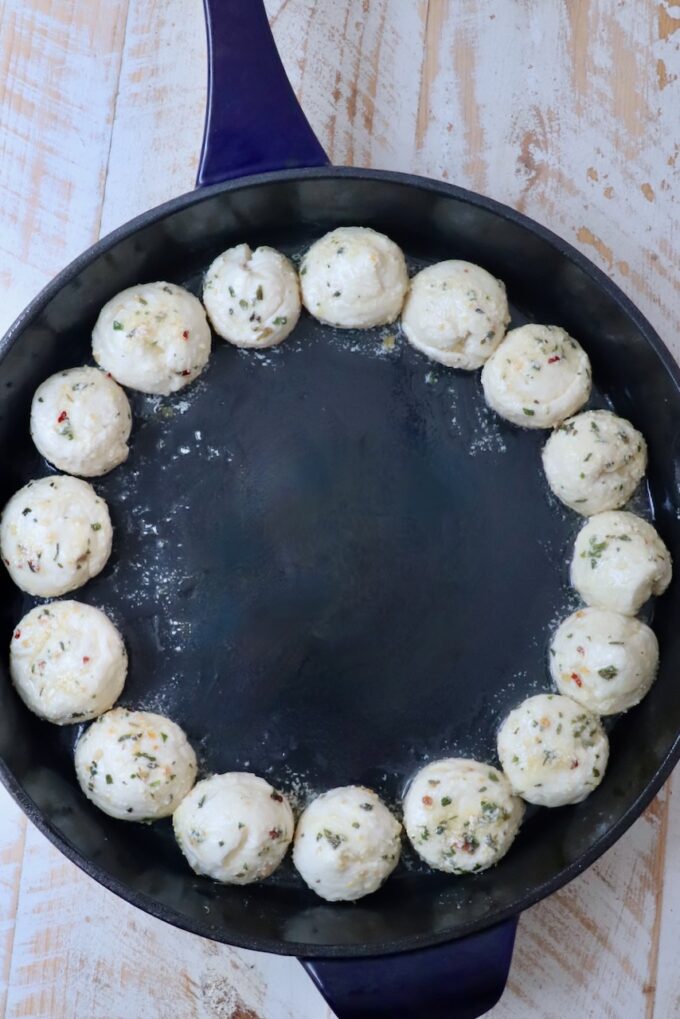 balls of seasoned dough in a cast iron skillet