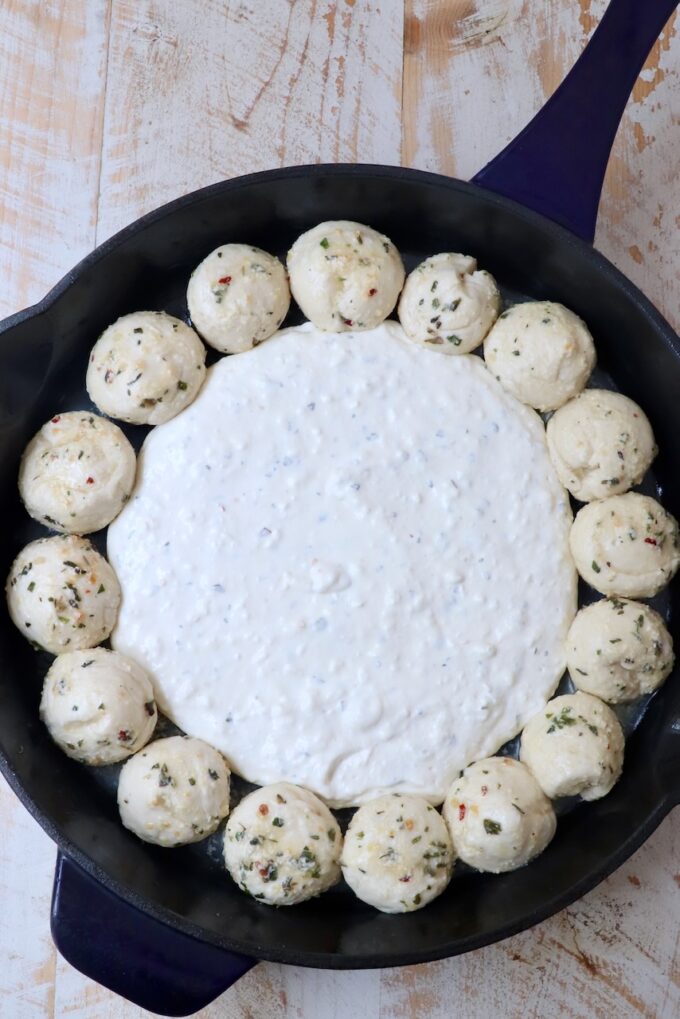 cream cheese mixture in the middle of a skillet surrounded by balls of dough