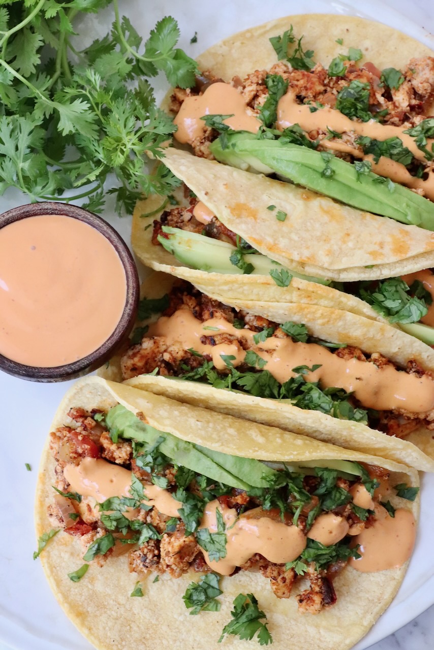 crumbled tofu tacos topped with chipotle sauce on a plate