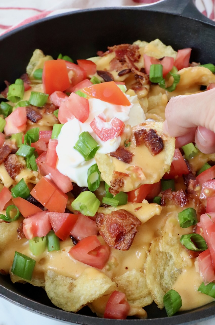 Irish nachos in a cast iron skillet topped with sour cream