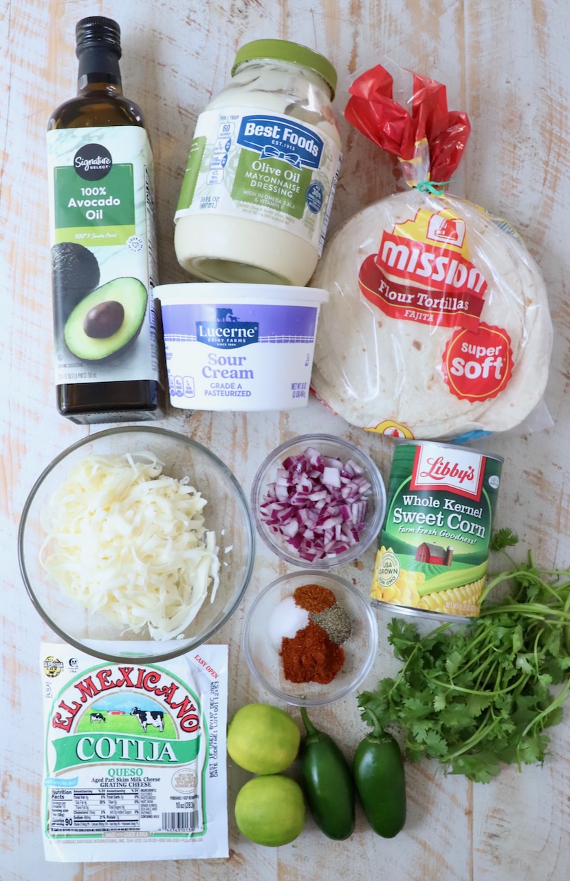 ingredients for Mexican street corn taquitos on a white wood board