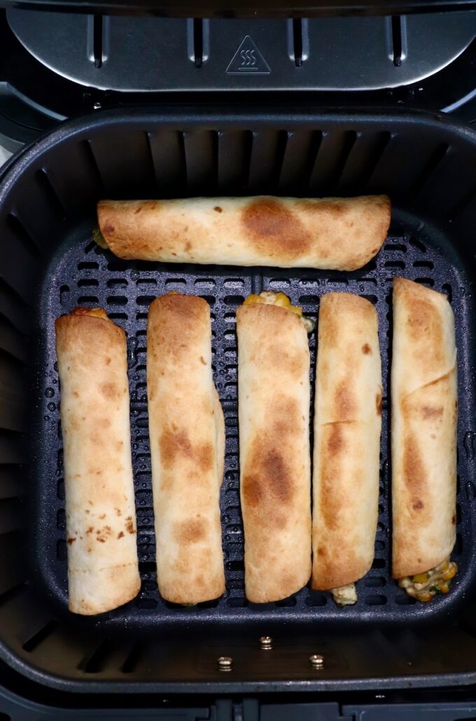 cooked taquitos in an air fryer basket