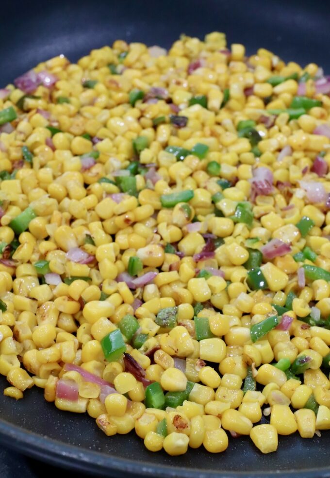 cooked corn kernels, diced onions and jalapenos in a skillet