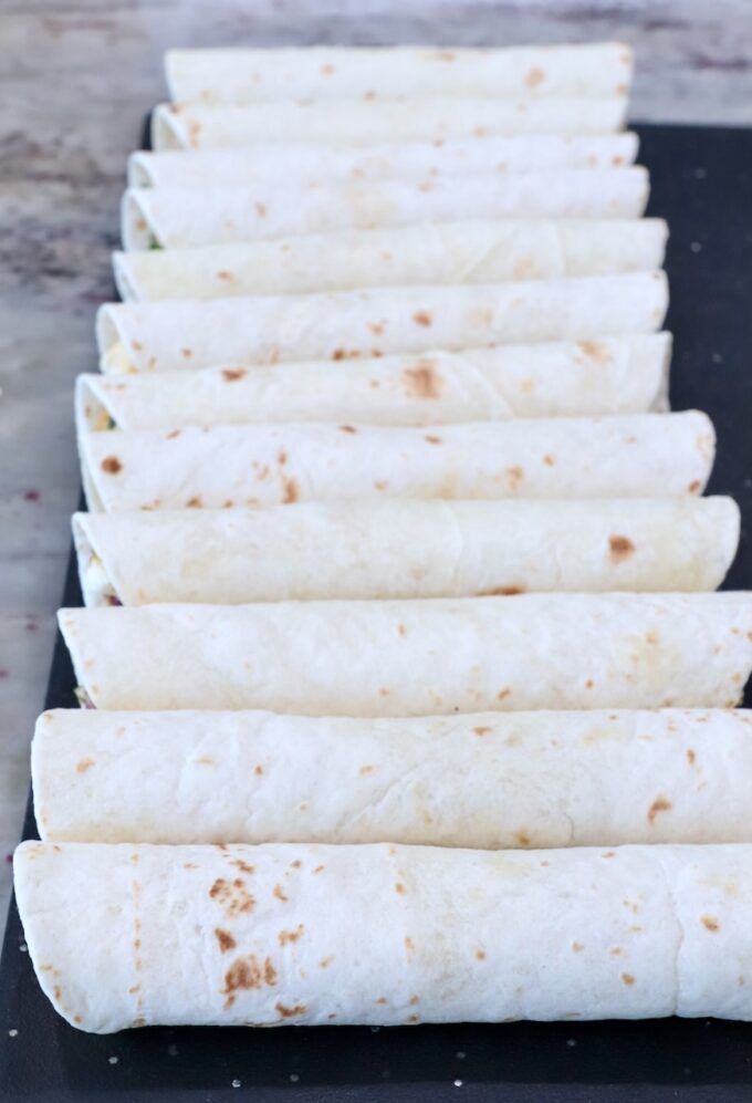 uncooked rolled-up taquitos on a cutting board