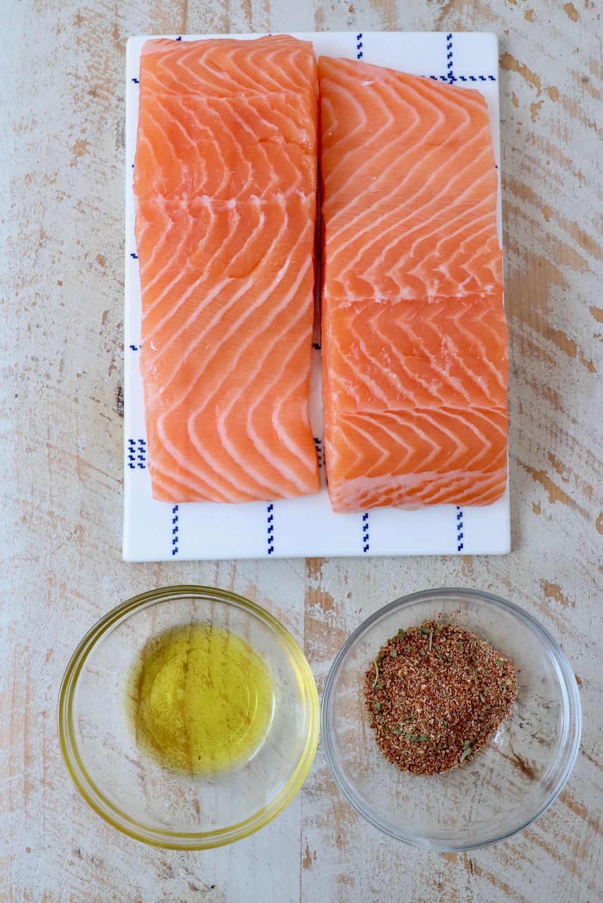 salmon filets next to small bowl of seasoning and small bowl of oil