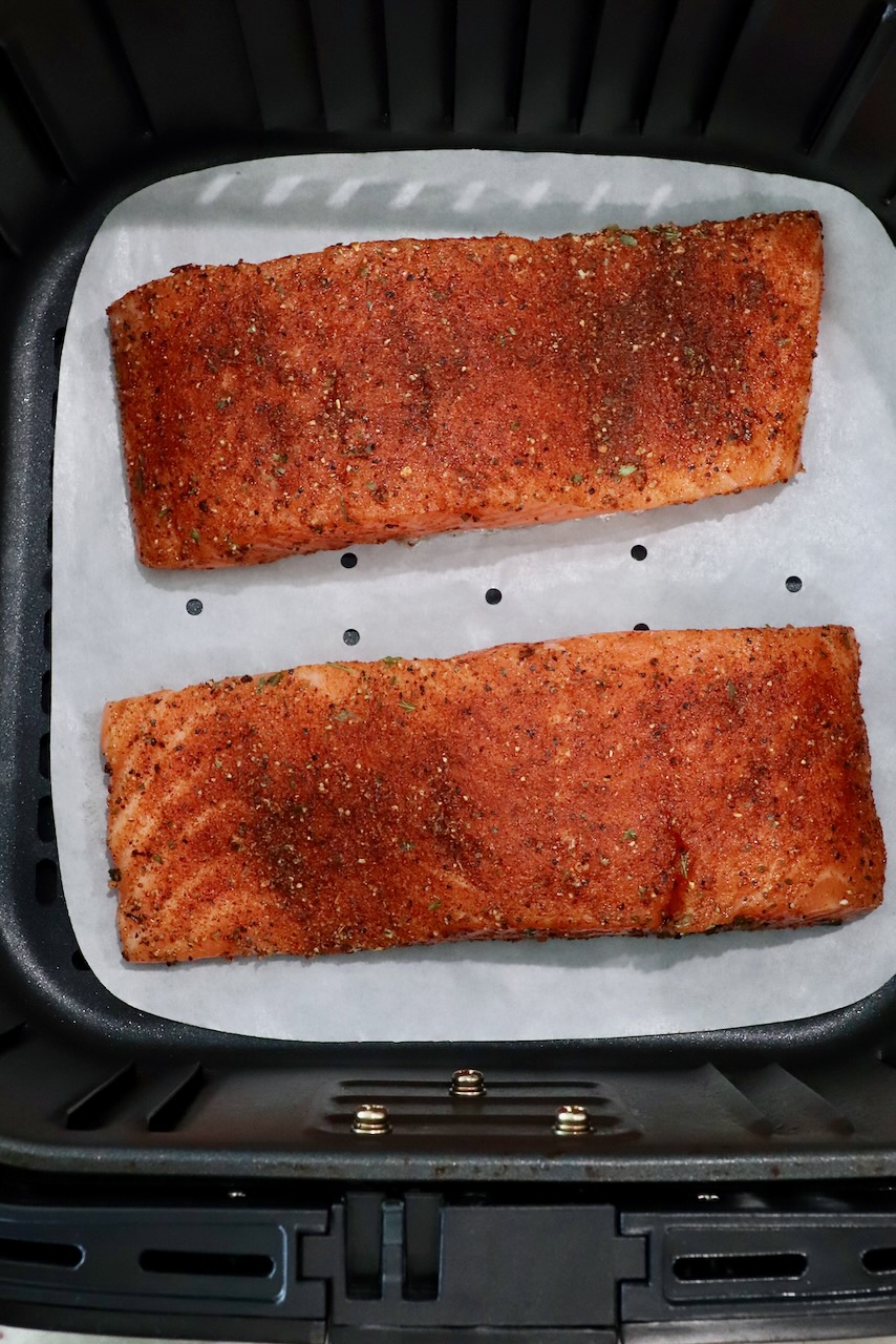 seasoned salmon filets in an air fryer basket