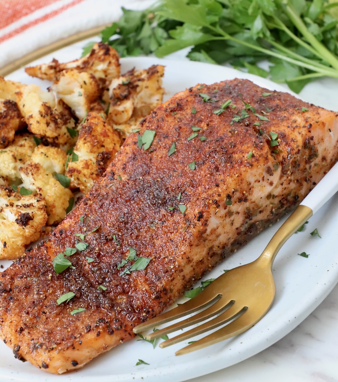 cooked salmon filet on plate with fork and roasted cauliflower