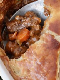 serving spoon in cooked beef pot pie in a baking dish