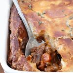 serving spoon in a beef pot pie in a baking dish