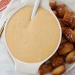 beer cheese dip in bowl with spoon, with pretzel bites on the side of the bowl