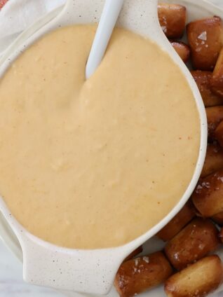 beer cheese dip in bowl with spoon, with pretzel bites on the side of the bowl