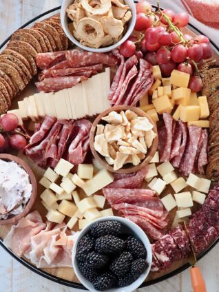 charcuterie board filled with meats, cheeses, crackers and fruits