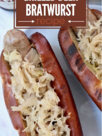 grilled bratwurst in pretzel bun topped with sauerkraut on a plate