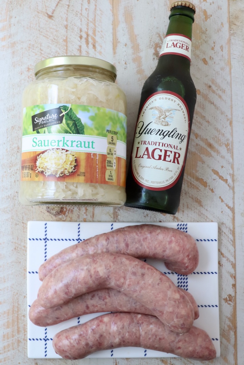 ingredients for beer brats on white wood board