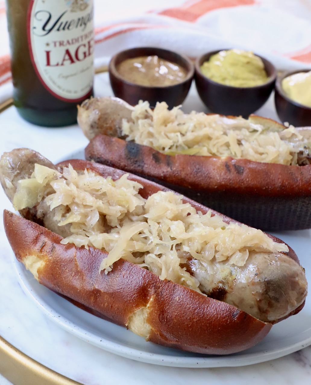 grilled bratwurst and sauerkraut on pretzel bun on plate