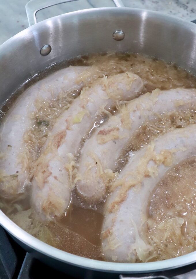 cooked bratwurst in pan with beer and sauerkraut