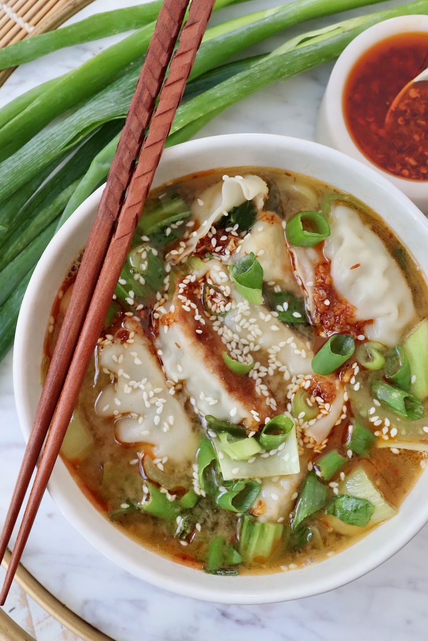 gyoza soup in a bowl with chopsticks on the side of the bowl