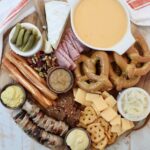 Oktoberfest themed charcuterie board with cheese, pretzels and mustard in small bowls