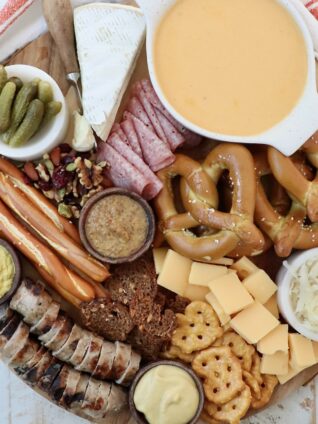 Oktoberfest themed charcuterie board with cheese, pretzels and mustard in small bowls