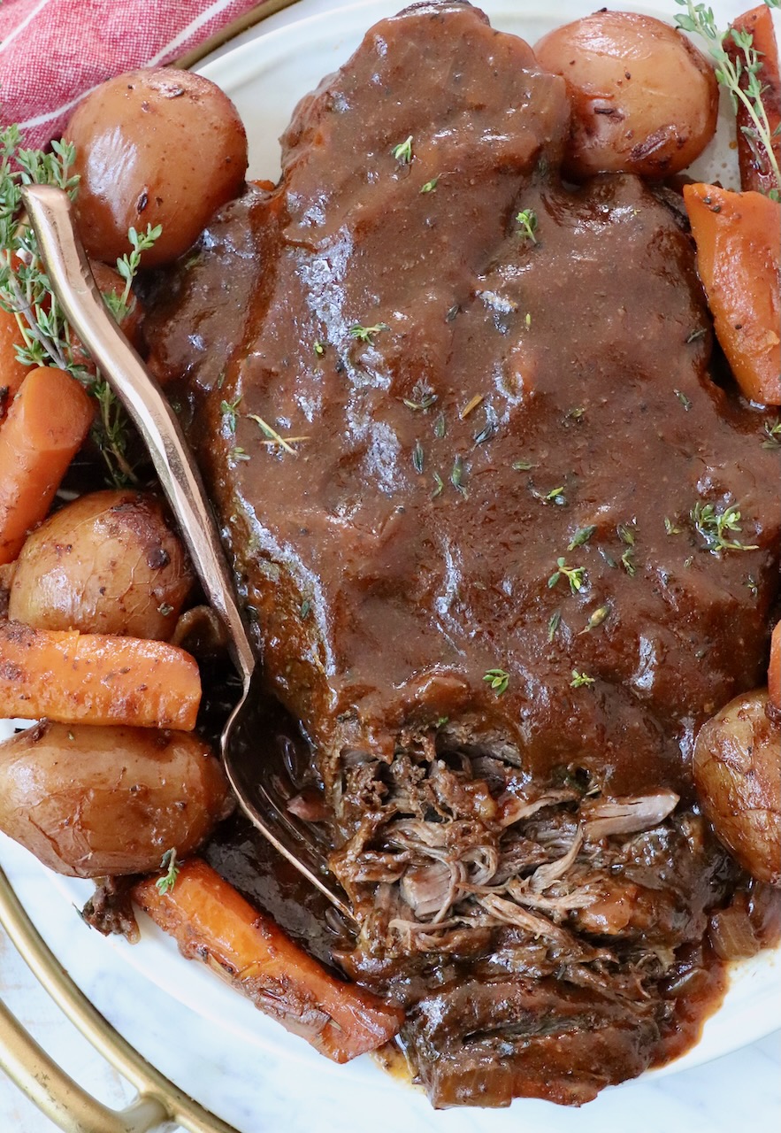 cooked pot roast on plate with fork and vegetables